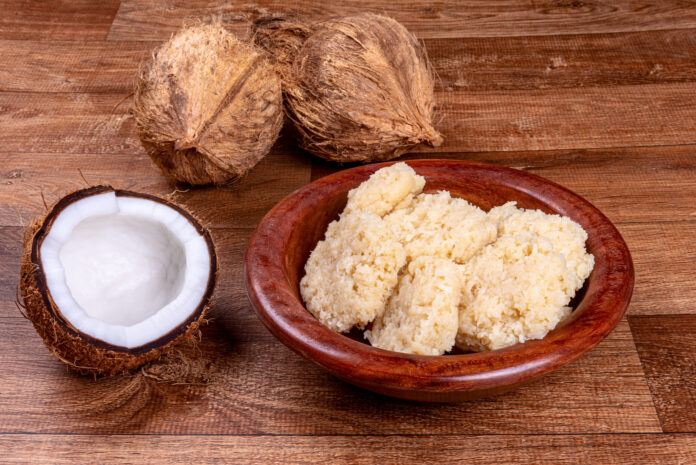 Cocada gaúcha com leite condensado em tigela de madeira, acompanhada de cocos frescos.